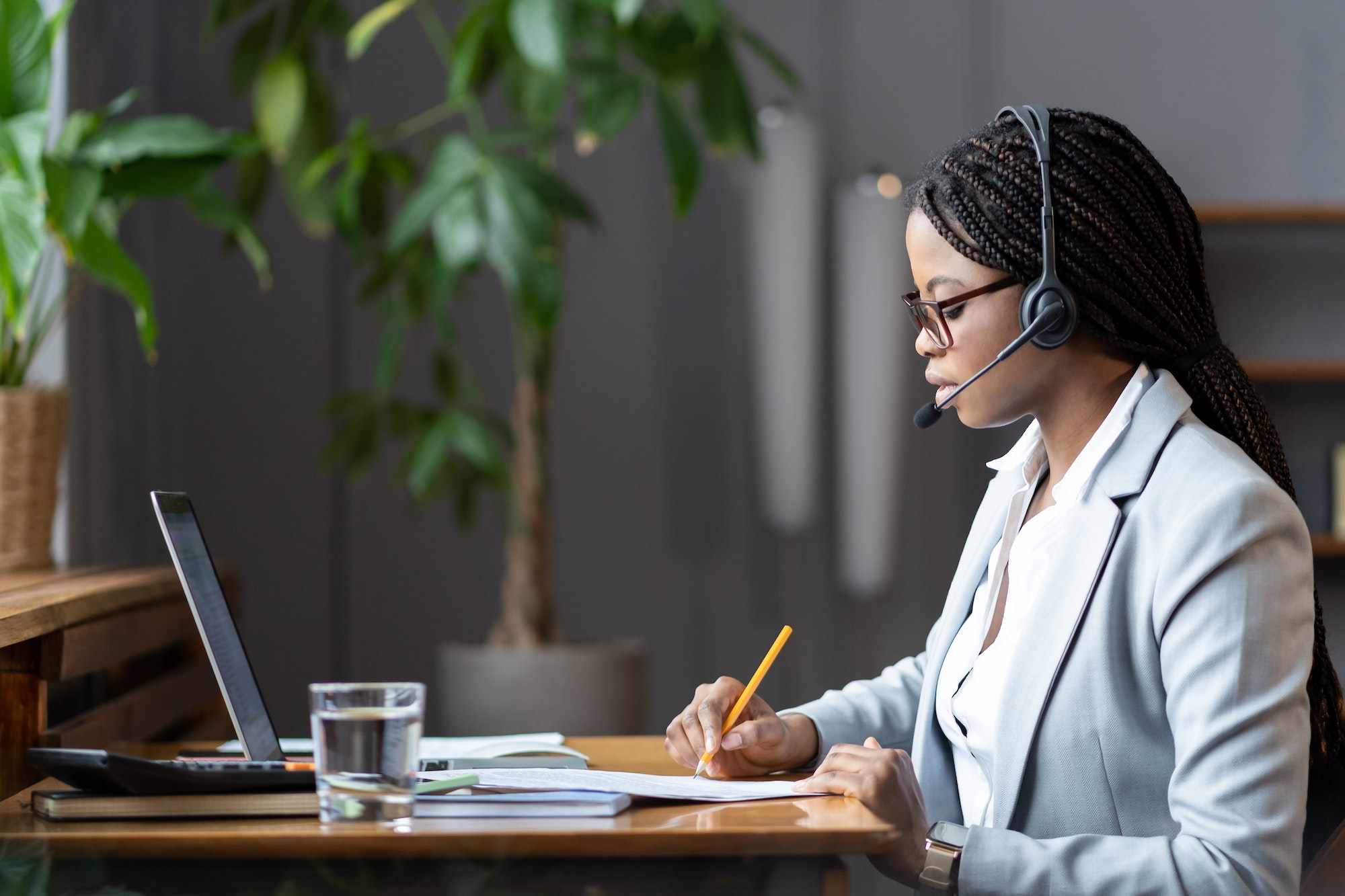 focused-african-female-home-based-virtual-assistant-in-headset-making-notes-during-online-meeting.jpg